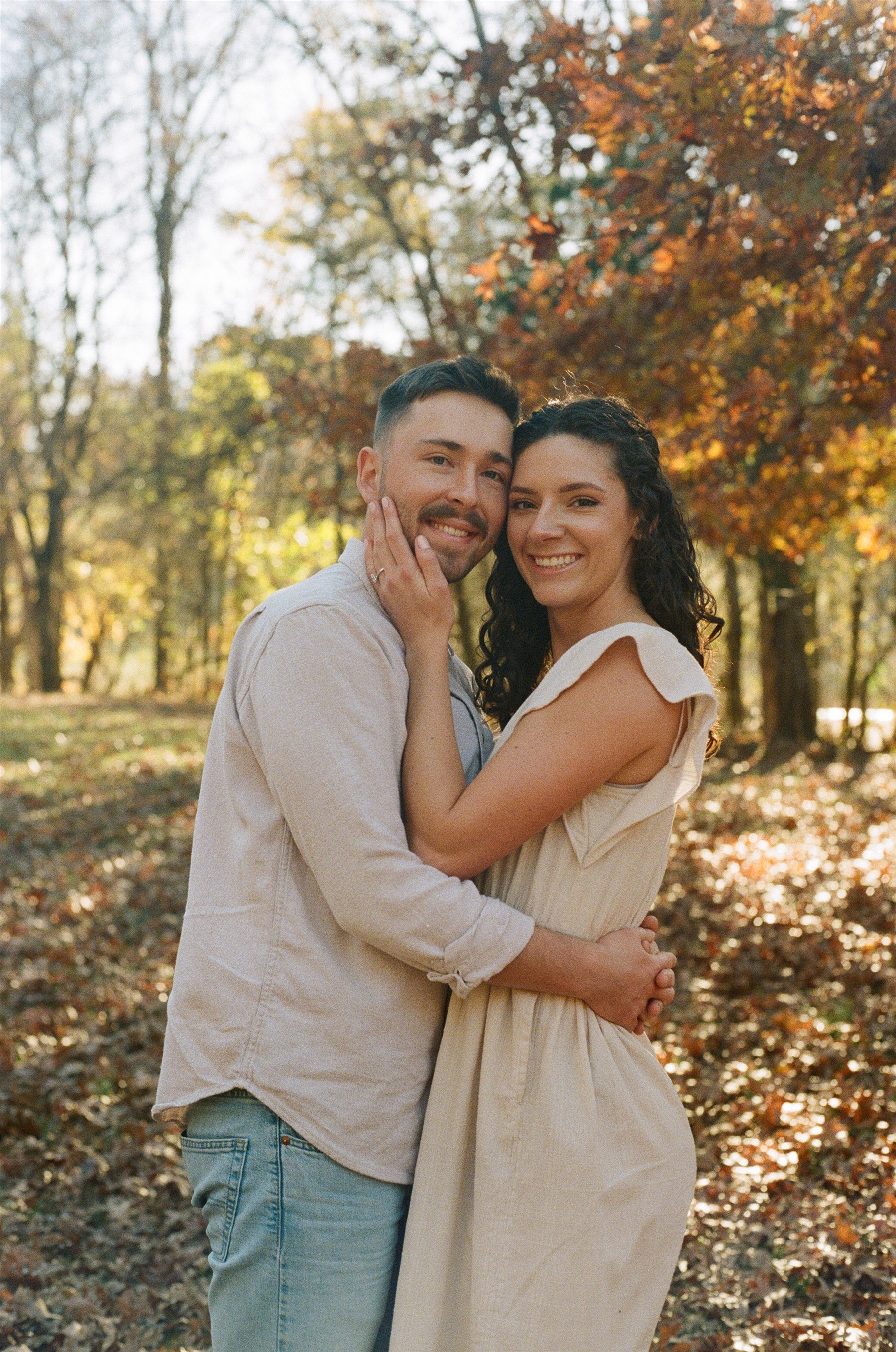 A couple embracing beneath autumn trees, photographed on film